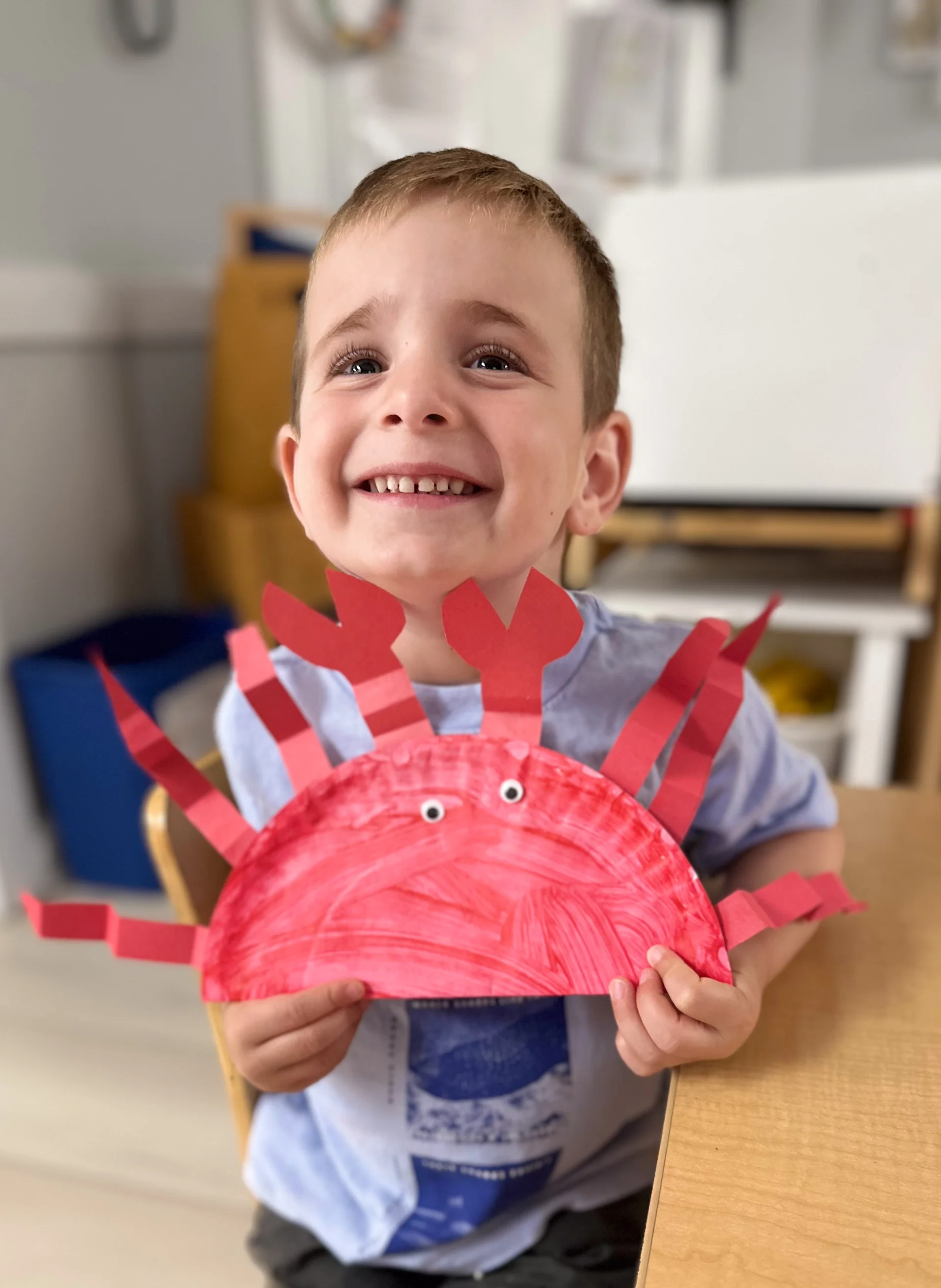 child showing his art work from summer camp